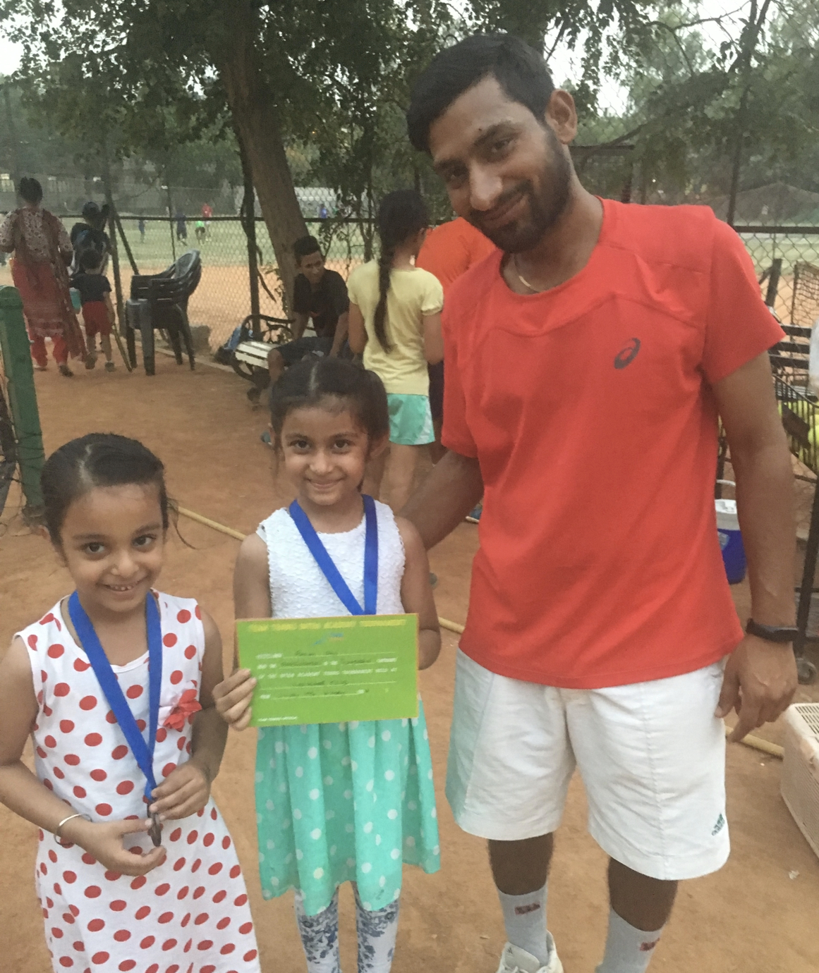 Priyal and her teammate with their medals and certificate, standing with their tennis coach